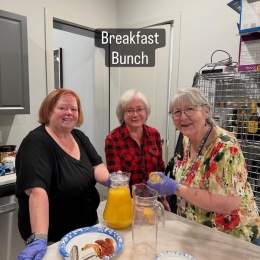 three women at a table with food and drinks