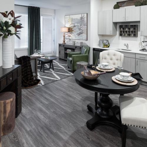 Beautiful living areas to match your lifestyle Model living room at Solana Lakewood senior living apartments near Denver, CO, featuring wood grain flooring and a table.