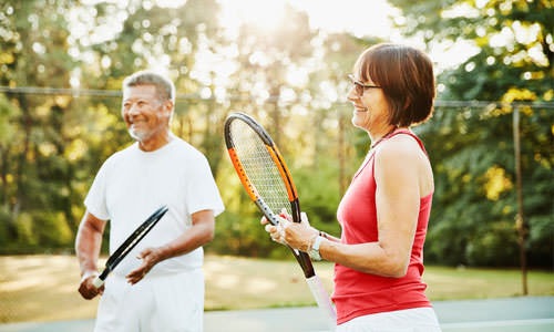 a couple holds tennis rackets on court